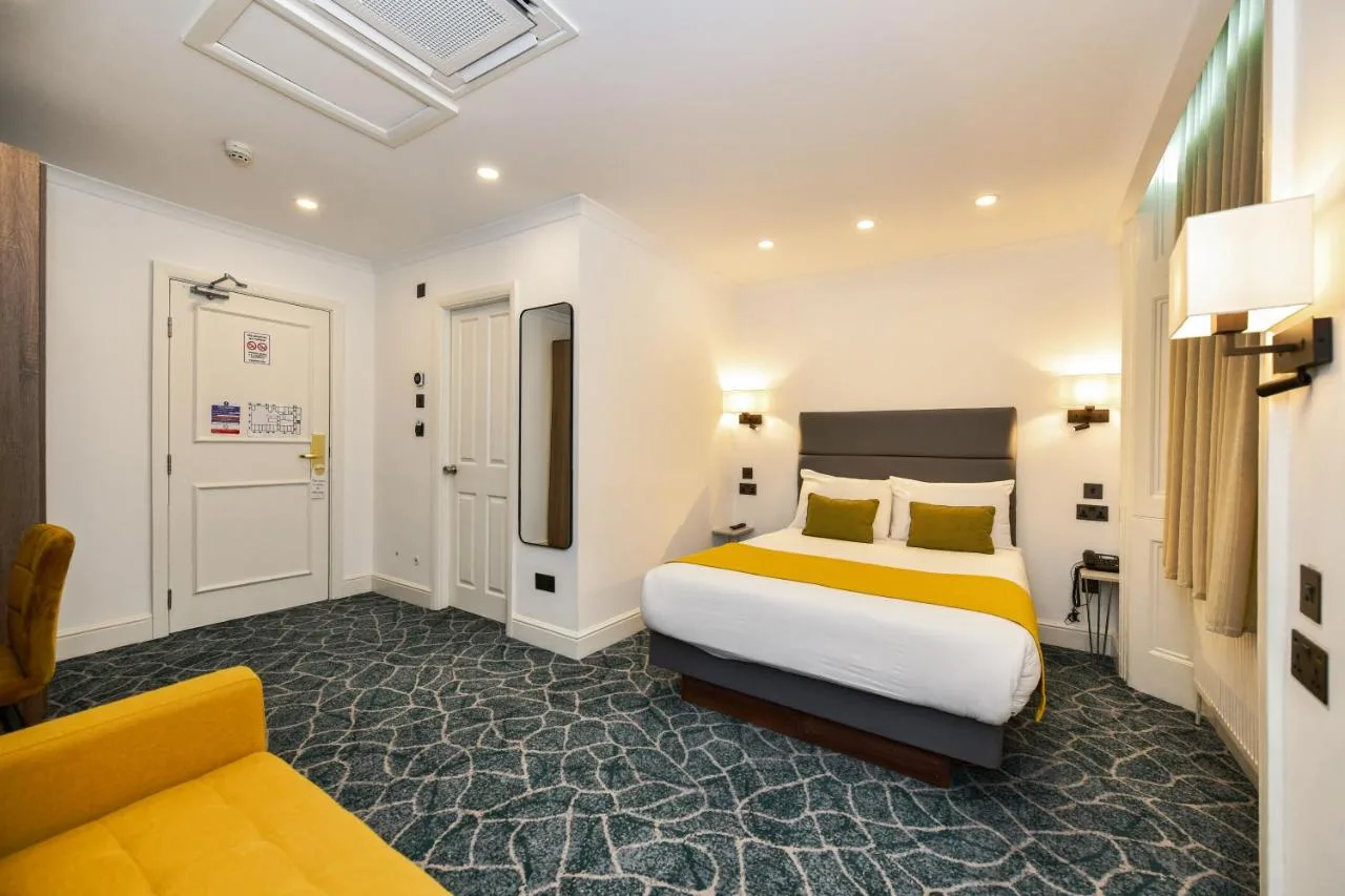 a hotel room with a bed and a couch at Park Avenue Bayswater Inn Hyde Park in London