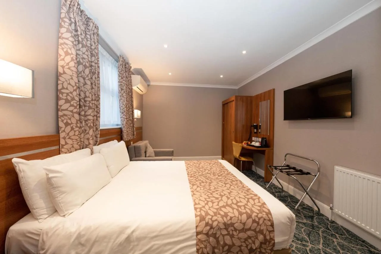 a hotel room with a bed and a television at Park Avenue Bayswater Inn Hyde Park in London